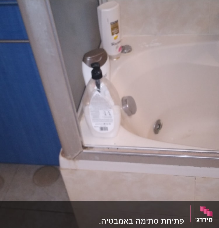 אמבטיה עם ברז ומקלחת, בקבוקי סבון על הקצה